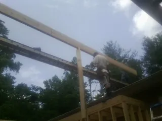 Carpenter setting a ridge beam over a new addition frame — Ice Dam Removal by Roofing Brothers in Claridge