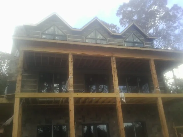 Dormers and porch framing on a large log home under construction — Roof Coating work by our crew in Claridge