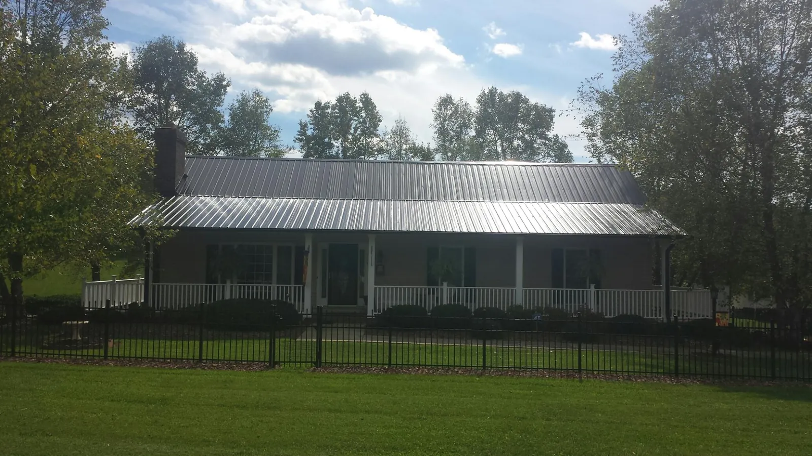 Gray metal roof on a brick ranch with a full width front porch — Gutter Guard Installation work by our crew in Claridge