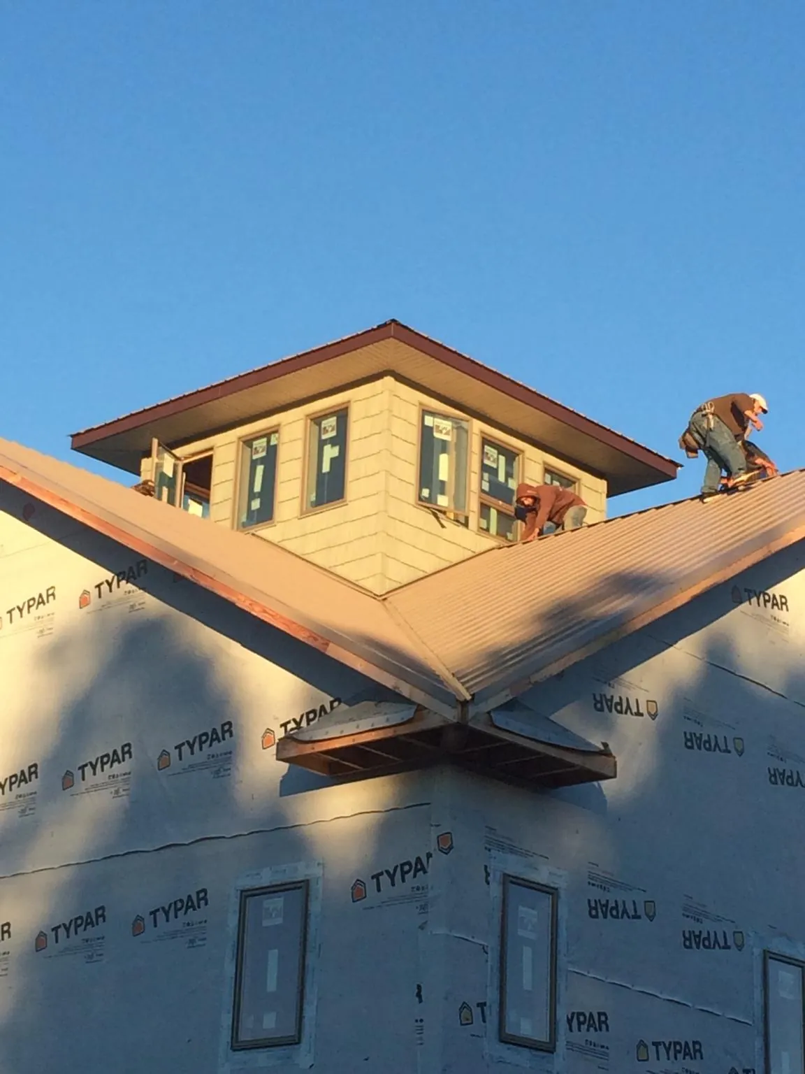 Roofers working around a rooftop cupola on a new metal roof at sunset — Roof Waterproofing in Claridge by Roofing Brothers
